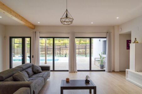 vista interior de un salón moderno con vistas al patio exterior con piscina de una casa prefabricada en madera